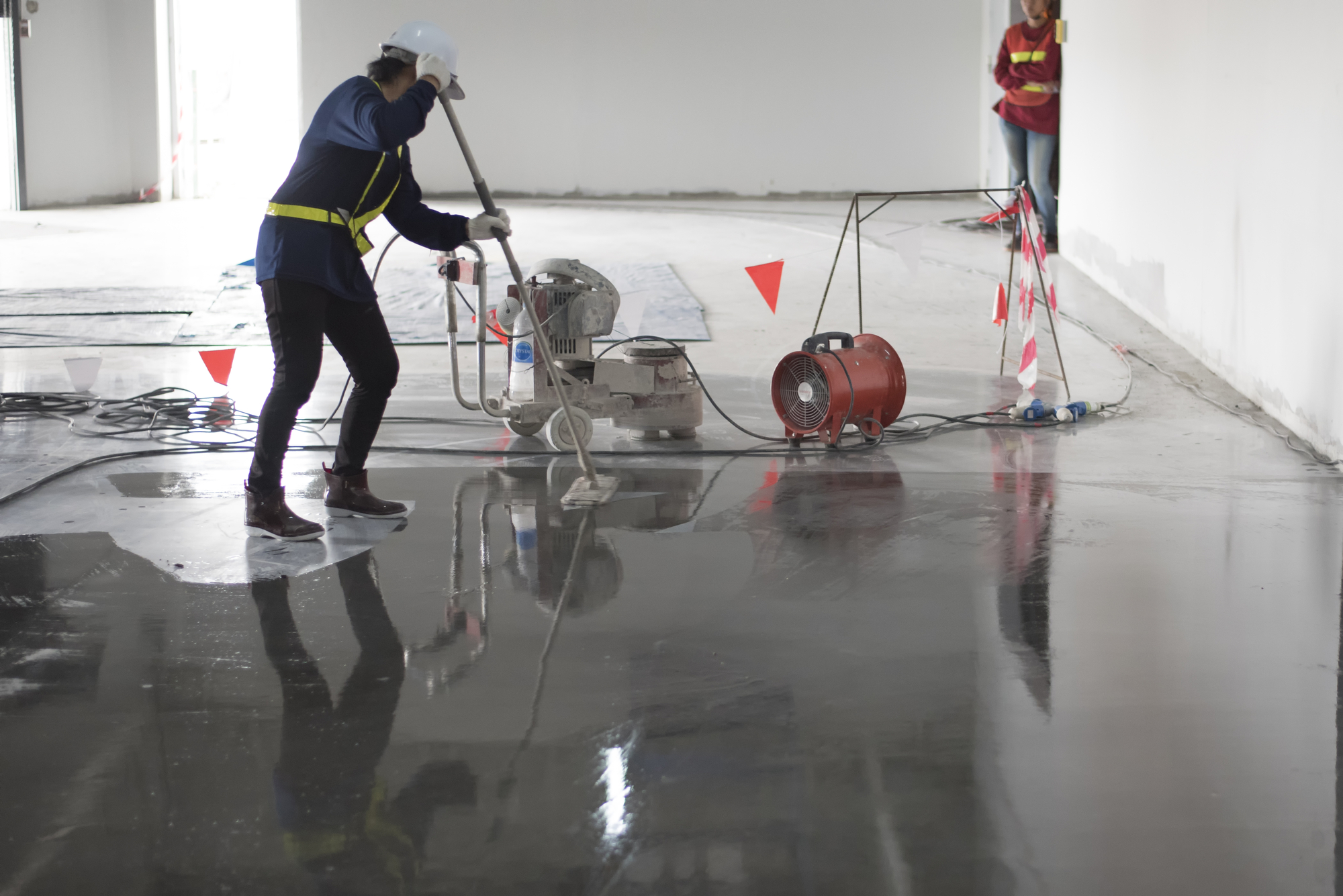 Construction worker painting epoxy flooring or floor hardener